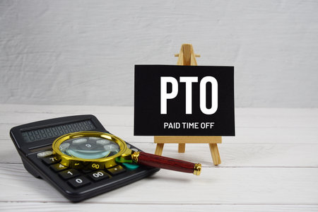 PTO abbreviation of Paid Time Off text with magnifying glass and calculator on wooden backgroundの写真素材