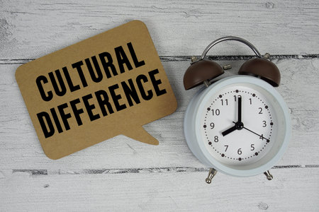 Cultural Difference text with alarm clock on wooden background