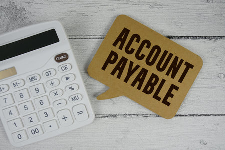 Accounts Payable (AP) text with calculator on wooden background