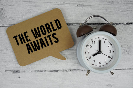 The World Awaits text with alarm clock on wooden backgroundの写真素材