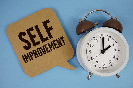 Self Improvement text with alarm clock on blue backgroundの写真素材