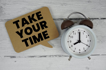 Take Your Time text with alarm clock on wooden background