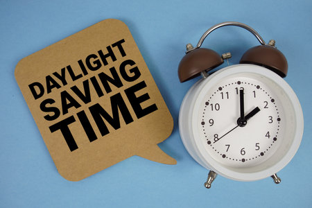 Daylight Saving Time text with alarm clock on blue backgroundの写真素材