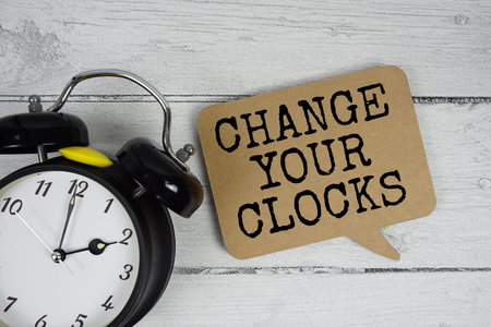 Change Your Clocks text with alarm clock on wooden background