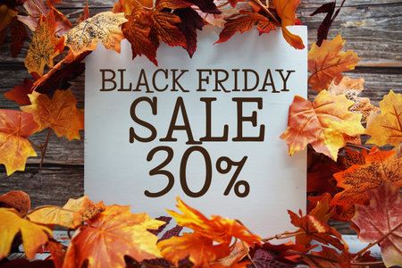 Black Friday Sale 30% off text with maple leaf decoration on wooden background