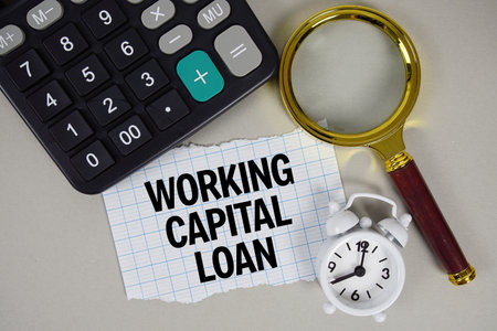 Working Capital Loan text with alarm clock, magnifying glass anc calculator on gray backgroundの写真素材