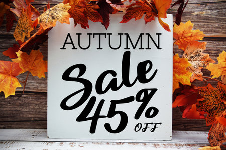 Autumn Sale 45% off text with maple leaf decoration on wooden backgroundの写真素材