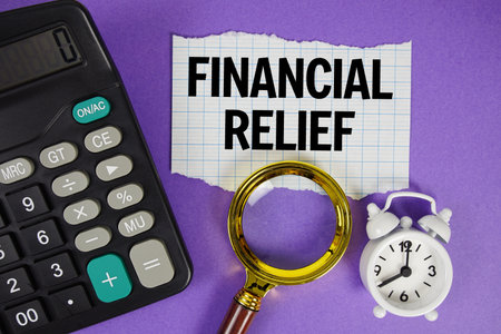 Financial Relief text with alarm clock, magnifying glass anc calculator on purple backgroundの写真素材