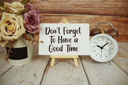 Don't Forget To Have a Good Time text with easel and alarm clock on wooden backgroundの写真素材