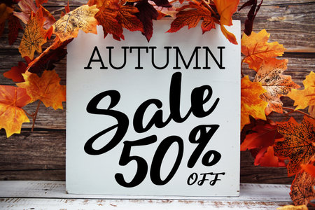 Autumn Sale 50% off text with maple leaf decoration on wooden backgroundの写真素材