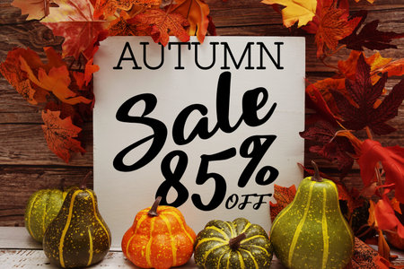 Autumn Sale 85% off text with maple leaf decoration on wooden background