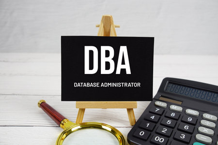 DBA Database Administrator text with magnifying glass and calculator on wooden backgroundの写真素材