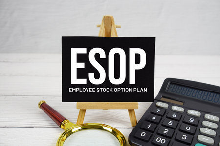 ESOP Employee Stock Option Plan text with magnifying glass and calculator on wooden backgroundの写真素材