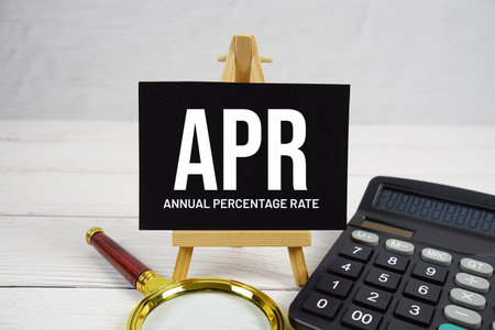 APR Annual Percentage Rate text with magnifying glass and calculator on wooden backgroundの写真素材