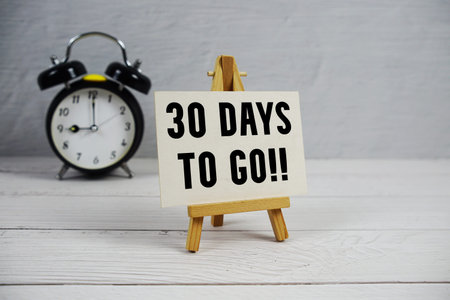 30 Days To Go! text with easel and alarm clock on wooden backgroundの写真素材