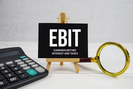 EBIT abbreviation of Earnings Before Interest and Taxes text with magnifying glass and calculator on wooden backgroundの写真素材