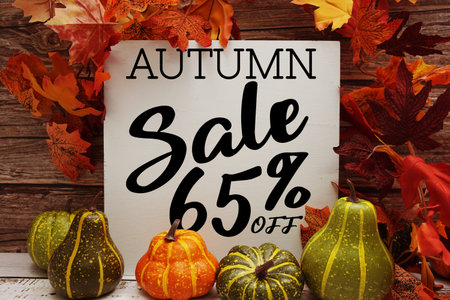 Autumn Sale 65% off text with maple leaf decoration on wooden backgroundの写真素材