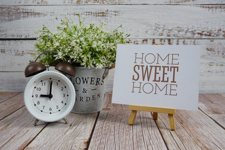 Home Sweet Home text with alarm clock on wooden backgroundの写真素材