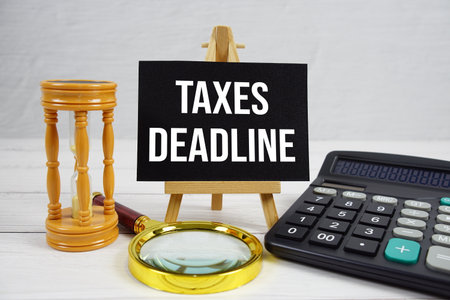 Taxes Deadline text with magnifying glass and calculator on wooden backgroundの写真素材