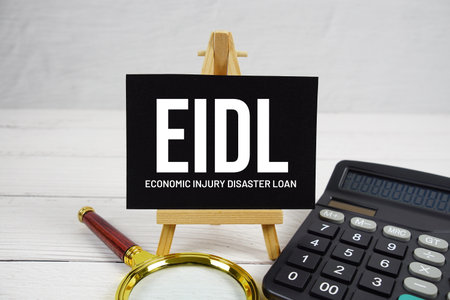 EIDL Economic Injury Disaster Loan text with magnifying glass and calculator on wooden backgroundの写真素材