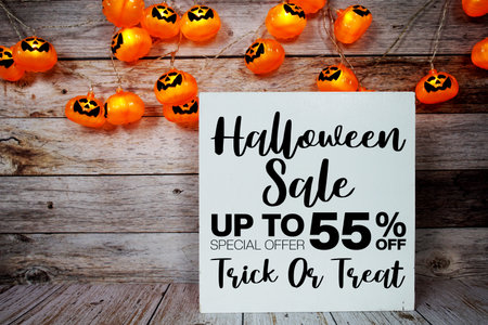 Halloween Sale 55% off text with LED pumpkin decoration on wooden background