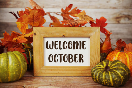 Welcome October text with maple leaf decoration on wooden backgroundの写真素材