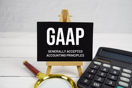 GAAP Generally Accepted Accounting Principles text with magnifying glass and calculator on wooden backgroundの写真素材