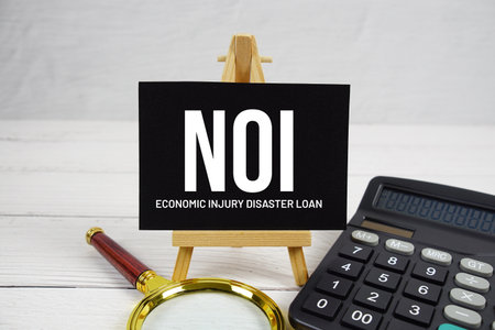 NOI Net Operating Income text with magnifying glass and calculator on wooden backgroundの写真素材