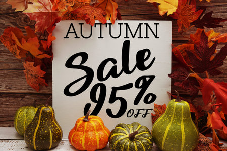 Autumn Sale 95% off text with maple leaf decoration on wooden background