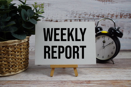 Weekly Report text with alarm clock on wooden backgroundの写真素材