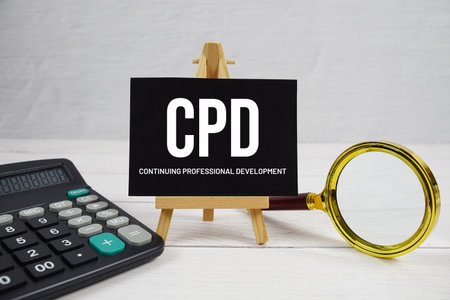 CPD abbreviation of Continuing Professional Development text with magnifying glass and calculator on wooden backgroundの写真素材