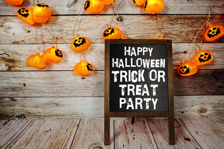 Happy Halloween Trick or Treat text on blackboard easel with LED pumpkin decoration on wooden backgroundの写真素材