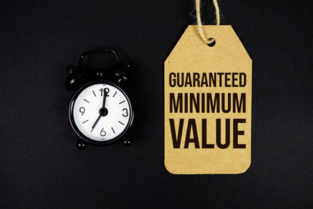 Guaranteed Minimum Value text on price tag with alarm clock on black backgroundの写真素材