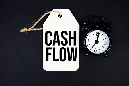 Cash Flow text on price tag with alarm clock on black backgroundの写真素材