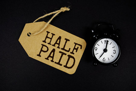 Half Paid text on price tag with alarm clock on black background