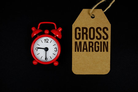 Gross Margin text on price tag with alarm clock on black backgroundの写真素材