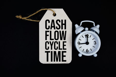 Cash Flow Cycle Time text on price tag with alarm clock on black backgroundの写真素材
