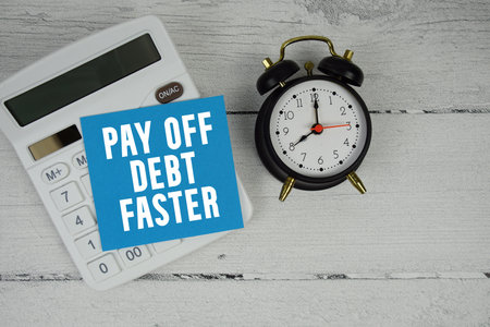 Pay Off Debt Faster text with calculator and alarm clock  on wooden backgroundの写真素材