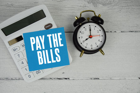 Pay The Bills text with calculator and alarm clock  on wooden backgroundの写真素材