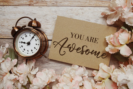 You are Awesome text with alarm clock and flowers decoration on wooden backgroundの写真素材