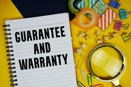 Guarantee And Warranty text with magnifying glass and stationery on yellow background