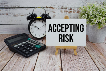 Accepting Risk text with alarm clock and calculator on wooden backgroundの写真素材