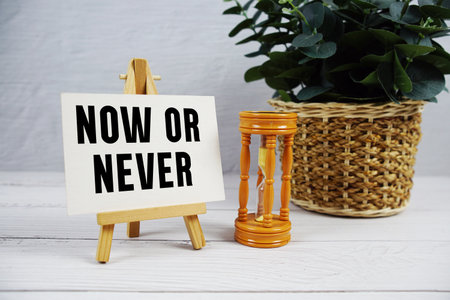 Now or Never text with hourglass on wooden backgroundの写真素材