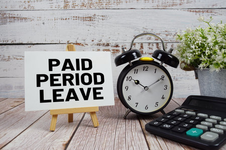 Paid Period Leave text with alarm clock and calculator on wooden backgroundの写真素材