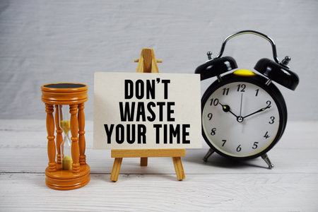 Don't Waste Your Time text with hourglass and alarm clock on wooden backgroundの写真素材