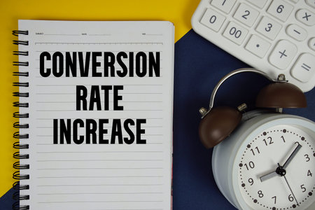 Conversion Rate Increase text written on notepad with calculator and alarm clock on navy blue...