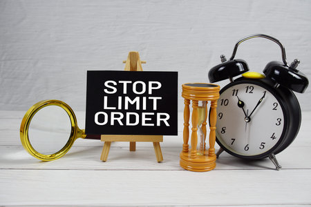 Stop Limit Order text with magnifing glass, hourglass and alarm clock on wooden backgroundの写真素材