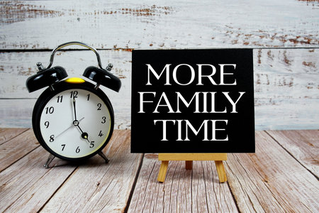 More Family Time text with easel and alarm clock on wooden backgroundの写真素材