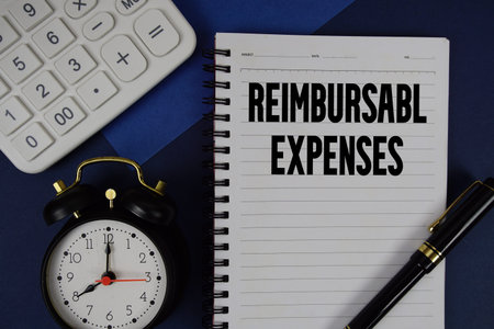 Reimbursable Expenses text written on notepad with calculator and alarm clock on navy blue...