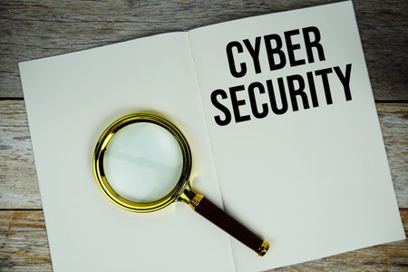 Cyber Security text message written on paper note with magnifying glass top view on wooden backgroundの写真素材